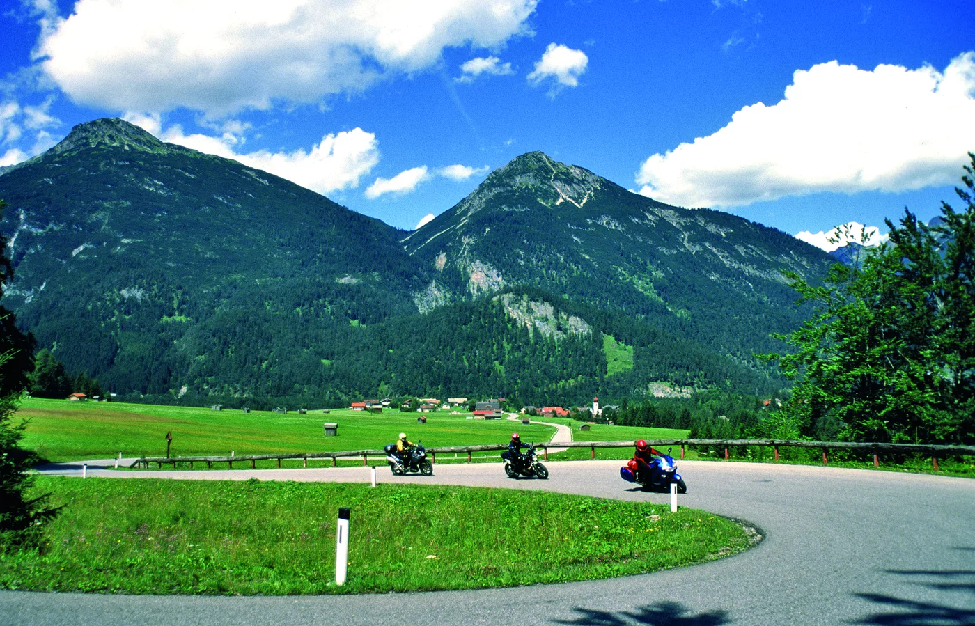 Motorräder in einer Kurve vor weitem Bergpanorama